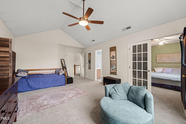 carpeted bedroom with lofted ceiling, ceiling fan, visible vents, and ensuite bathroom