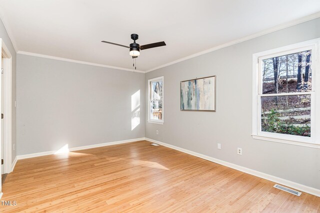 unfurnished room with light wood finished floors, visible vents, a wealth of natural light, and a ceiling fan