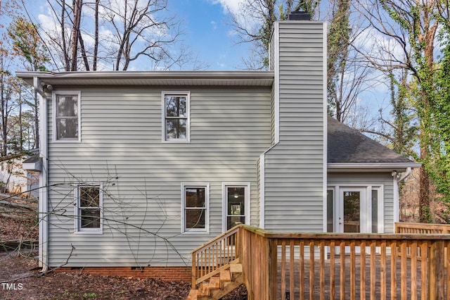 rear view of property with a wooden deck, roof with shingles, and a chimney