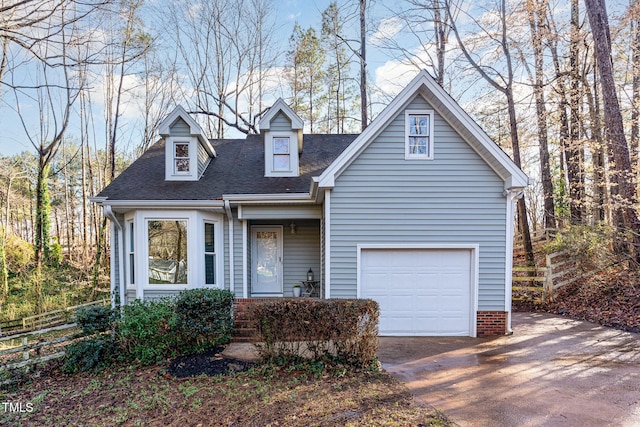 view of front facade with concrete driveway, fence, and a shingled roof