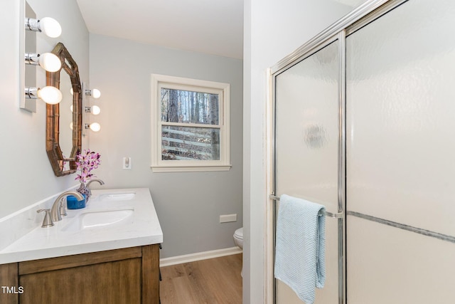 full bath featuring a sink, wood finished floors, toilet, and a stall shower