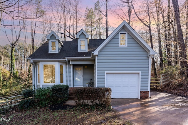 view of front facade with a shingled roof, concrete driveway, and fence