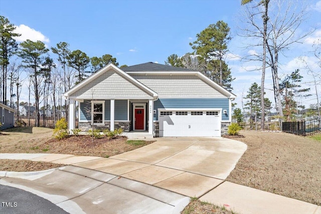 craftsman-style home featuring a garage, stone siding, fence, and concrete driveway