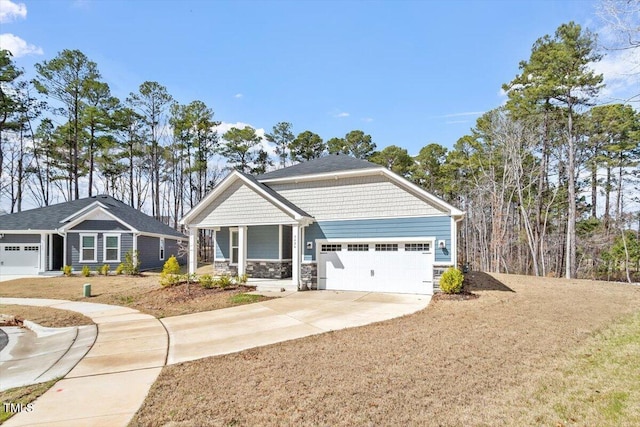 craftsman inspired home featuring a garage, concrete driveway, a porch, and stone siding