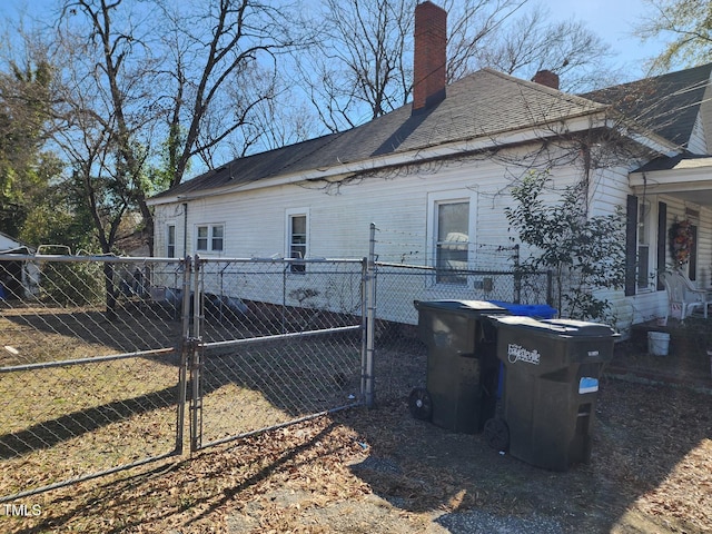 view of property exterior with a chimney, fence, and a gate