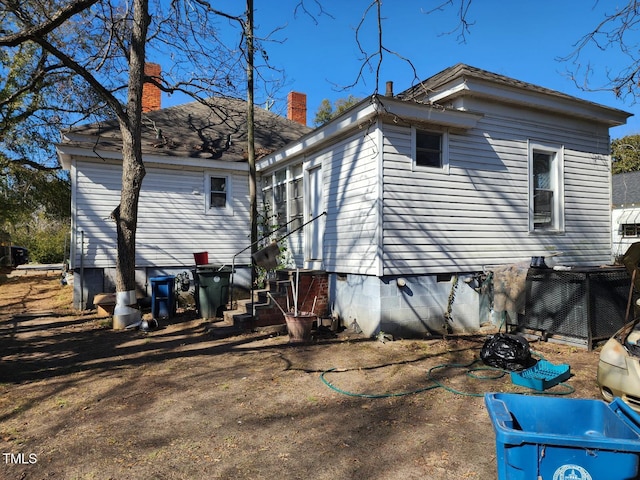 back of house featuring crawl space and a chimney