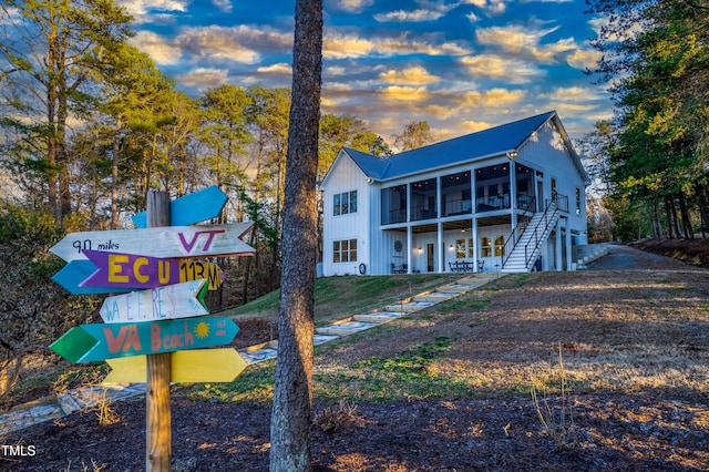 back of house at dusk with a sunroom and stairway