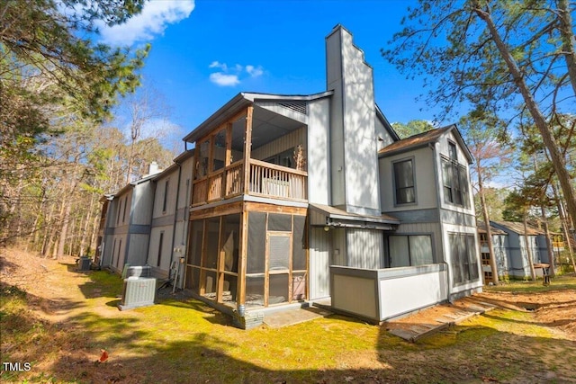 back of property featuring central AC, a chimney, a balcony, and a sunroom