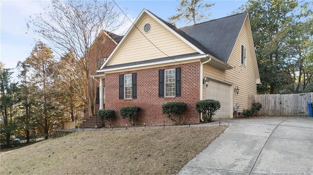 view of front facade featuring driveway, brick siding, a shingled roof, and fence