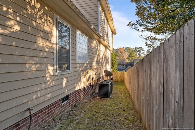 view of side of home with central AC and a fenced backyard