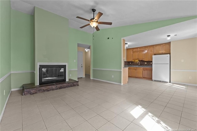 616 Missenburg Ct, Fayetteville, NC 28314 - unfurnished living room with light tile patterned floors, a ceiling fan, a glass covered fireplace, vaulted ceiling, and a sink