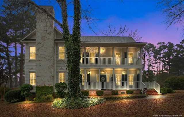 view of front facade featuring a balcony, a chimney, and a porch