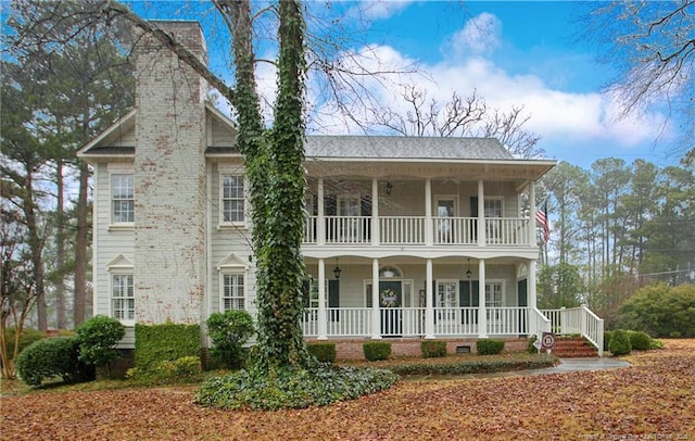 view of front of house featuring a balcony, covered porch, and a chimney