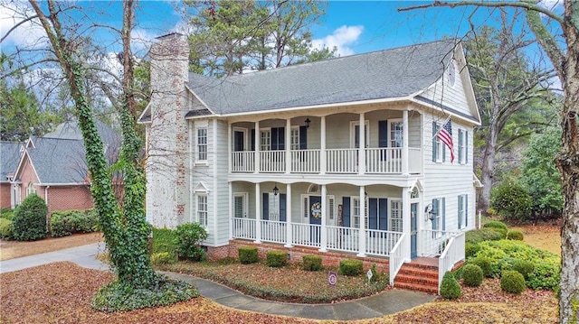 view of front facade with a porch, a chimney, and a balcony