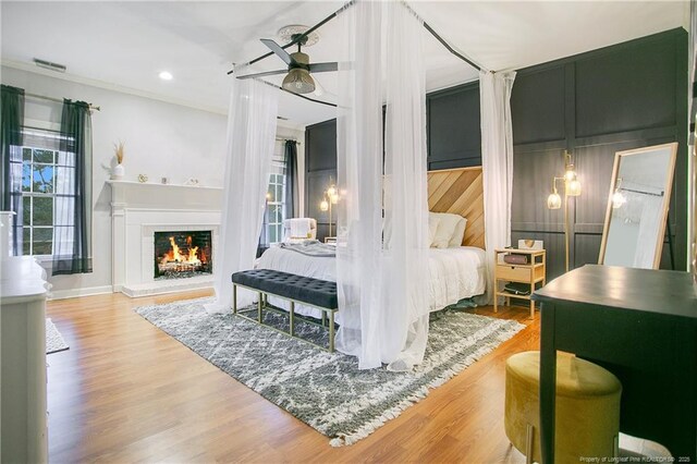 bedroom with crown molding, recessed lighting, visible vents, wood finished floors, and a lit fireplace