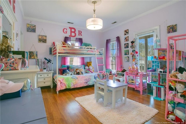 bedroom with visible vents, crown molding, and wood finished floors