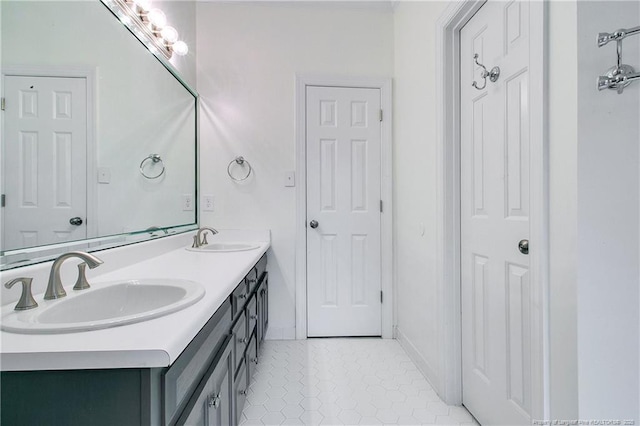 bathroom featuring baseboards, double vanity, a sink, and tile patterned floors