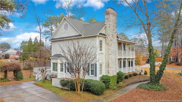 view of property exterior with a balcony, a chimney, and roof with shingles