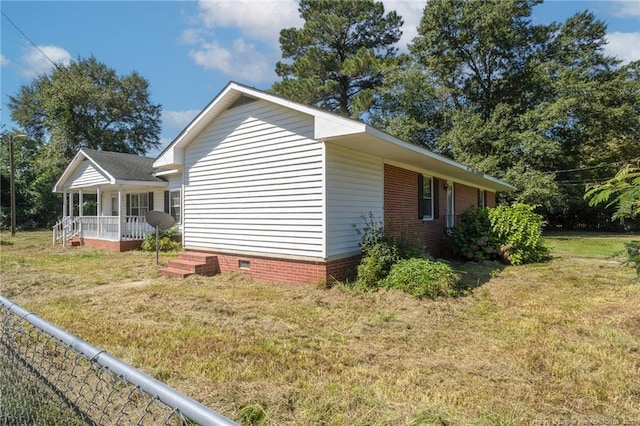 view of side of property with a yard, a porch, and crawl space