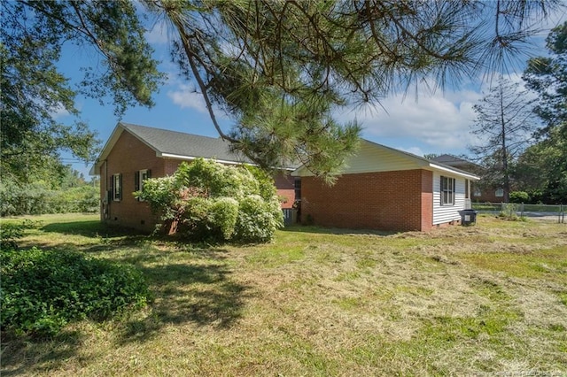 view of side of property featuring crawl space, a yard, fence, and brick siding