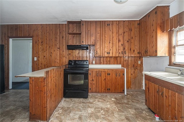 kitchen with brown cabinets, black range with electric stovetop, wood walls, a sink, and under cabinet range hood