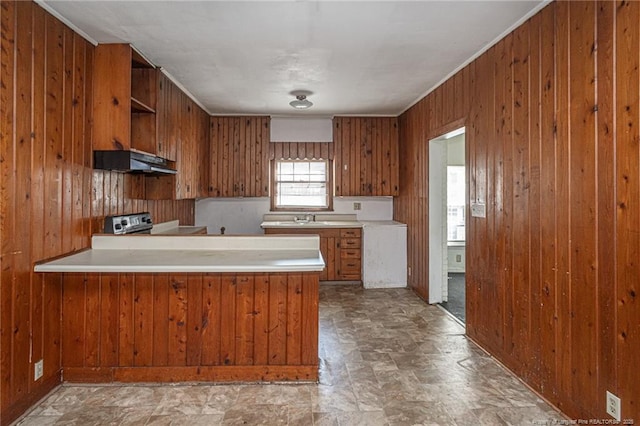 kitchen with brown cabinets, open shelves, light countertops, wood walls, and under cabinet range hood