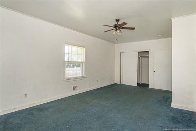 spare room with ceiling fan and dark colored carpet