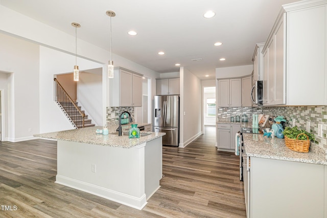 kitchen with stainless steel appliances, a sink, a peninsula, light wood finished floors, and recessed lighting