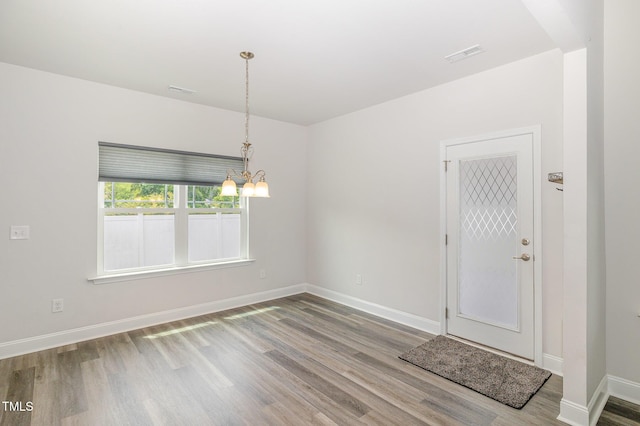 unfurnished room with wood finished floors, a chandelier, and baseboards