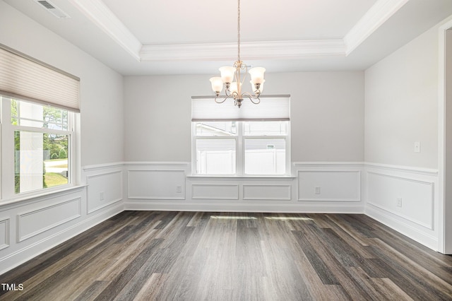 spare room featuring a tray ceiling, crown molding, a chandelier, dark wood-type flooring, and a wainscoted wall