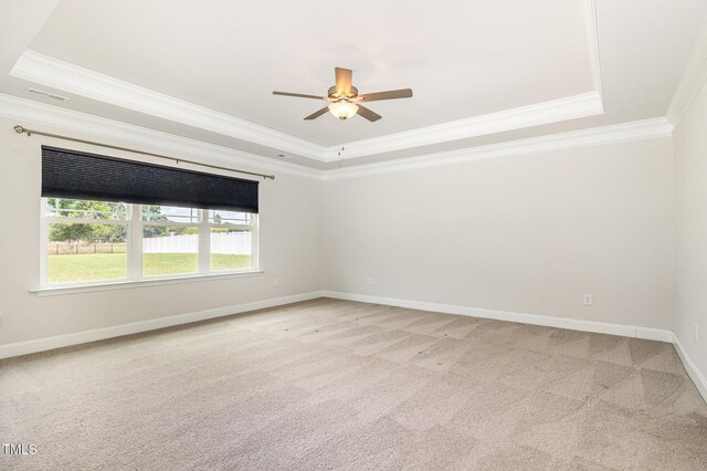 spare room with a raised ceiling, ornamental molding, light colored carpet, ceiling fan, and baseboards