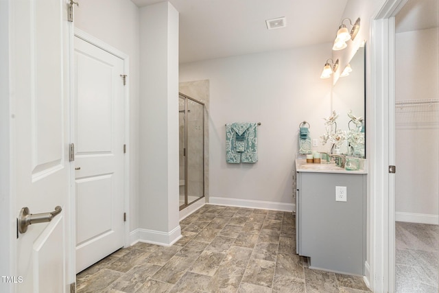 full bathroom featuring a shower stall, vanity, baseboards, and stone finish flooring