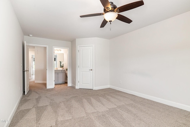 unfurnished bedroom with light carpet, baseboards, and ensuite bathroom