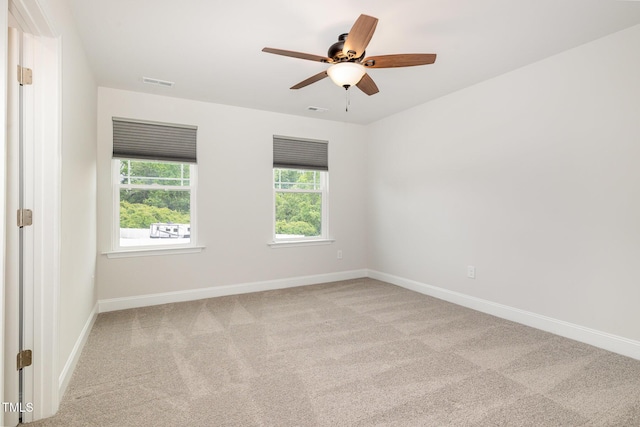carpeted empty room featuring baseboards and a ceiling fan