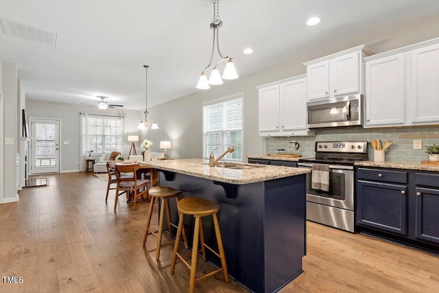 kitchen with appliances with stainless steel finishes, backsplash, a sink, and visible vents