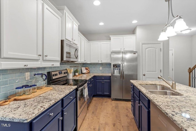 kitchen featuring stainless steel appliances, blue cabinetry, a sink, and white cabinetry