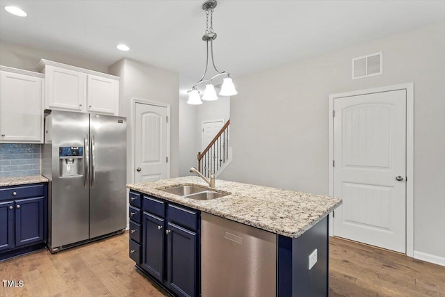 kitchen with stainless steel appliances, a sink, visible vents, and blue cabinets