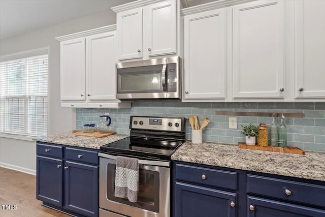 kitchen with tasteful backsplash, appliances with stainless steel finishes, white cabinets, and blue cabinets