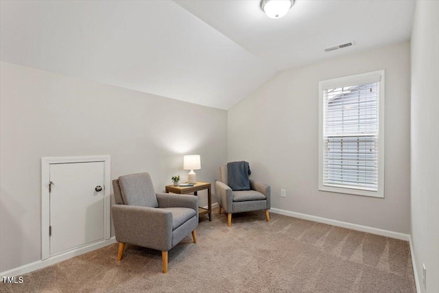 living area featuring vaulted ceiling, baseboards, visible vents, and light colored carpet