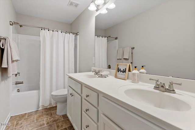 full bath with toilet, double vanity, visible vents, and a sink