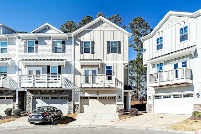 townhome / multi-family property featuring board and batten siding, stone siding, driveway, and an attached garage