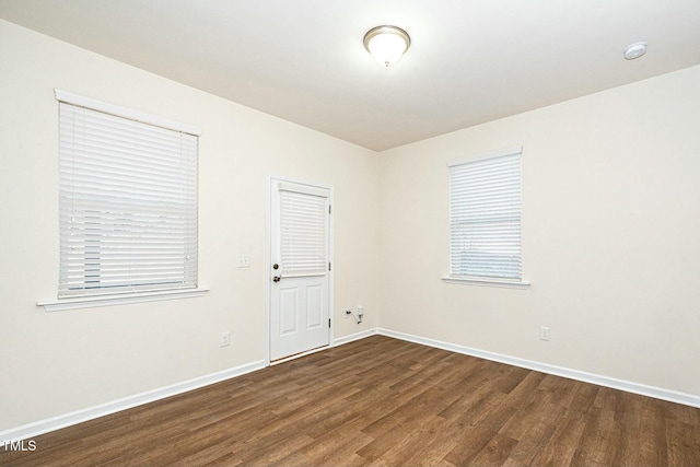 spare room with baseboards and wood finished floors