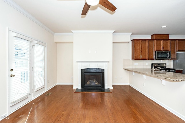 unfurnished living room featuring crown molding, baseboards, dark wood-type flooring, and a glass covered fireplace