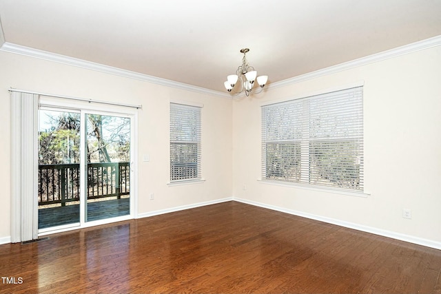 spare room featuring ornamental molding, dark wood-type flooring, and a notable chandelier