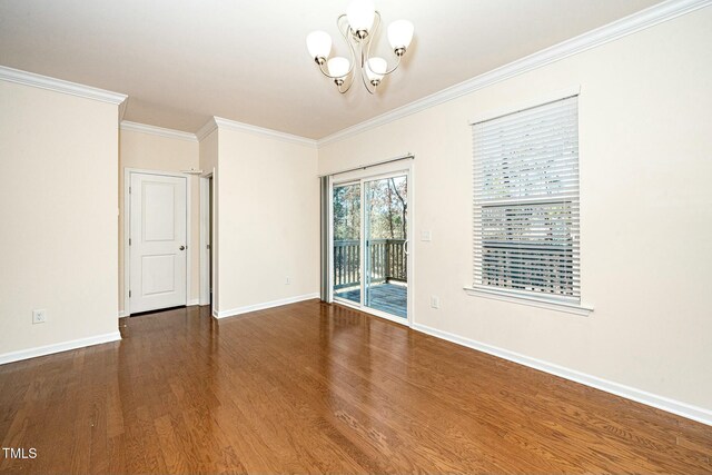 unfurnished room featuring a notable chandelier, crown molding, baseboards, and wood finished floors