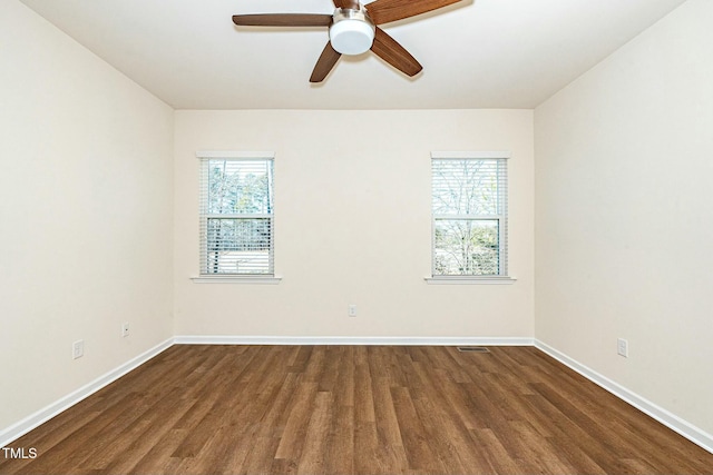 empty room featuring visible vents, baseboards, and dark wood finished floors