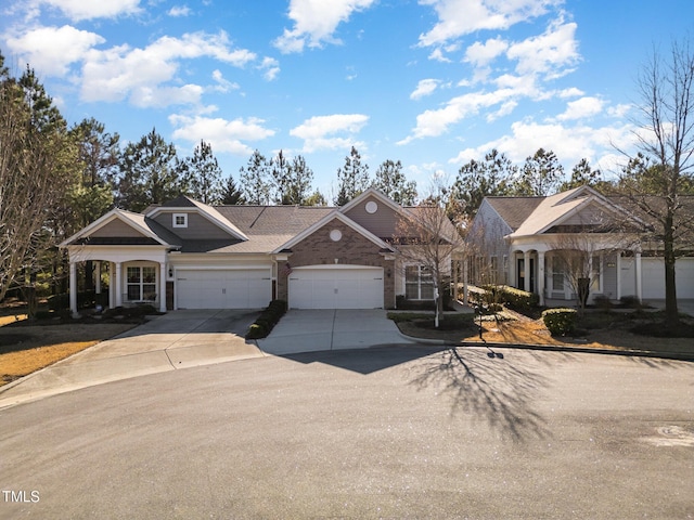 view of front of home with concrete driveway, brick siding, and an attached garage