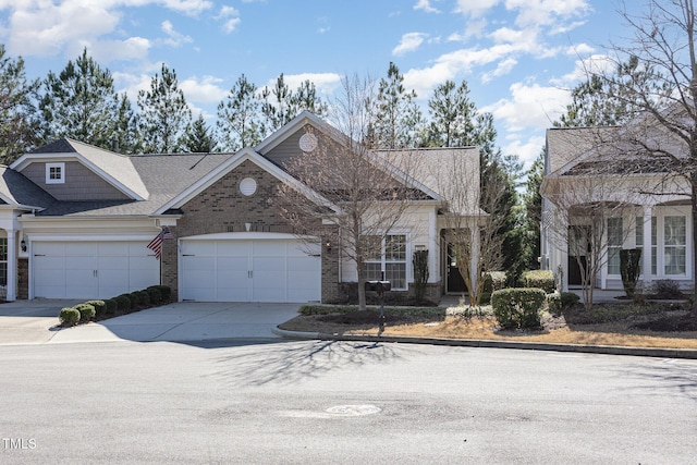 view of front of house with driveway, brick siding, roof with shingles, and an attached garage