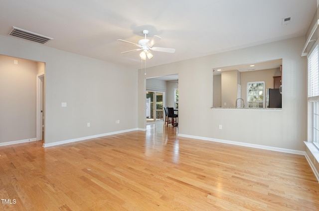 empty room with a ceiling fan, baseboards, visible vents, and light wood finished floors