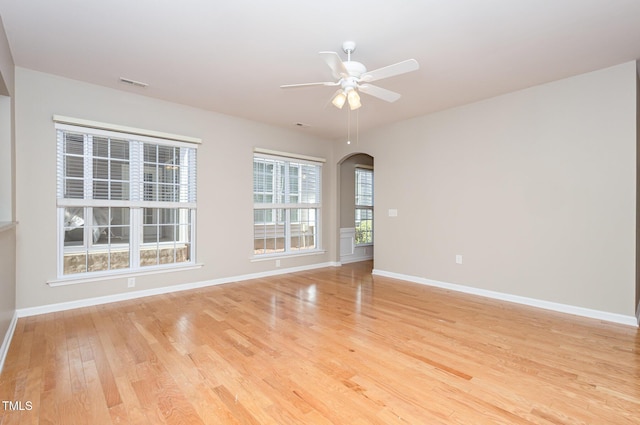 unfurnished room featuring arched walkways, ceiling fan, visible vents, baseboards, and light wood finished floors